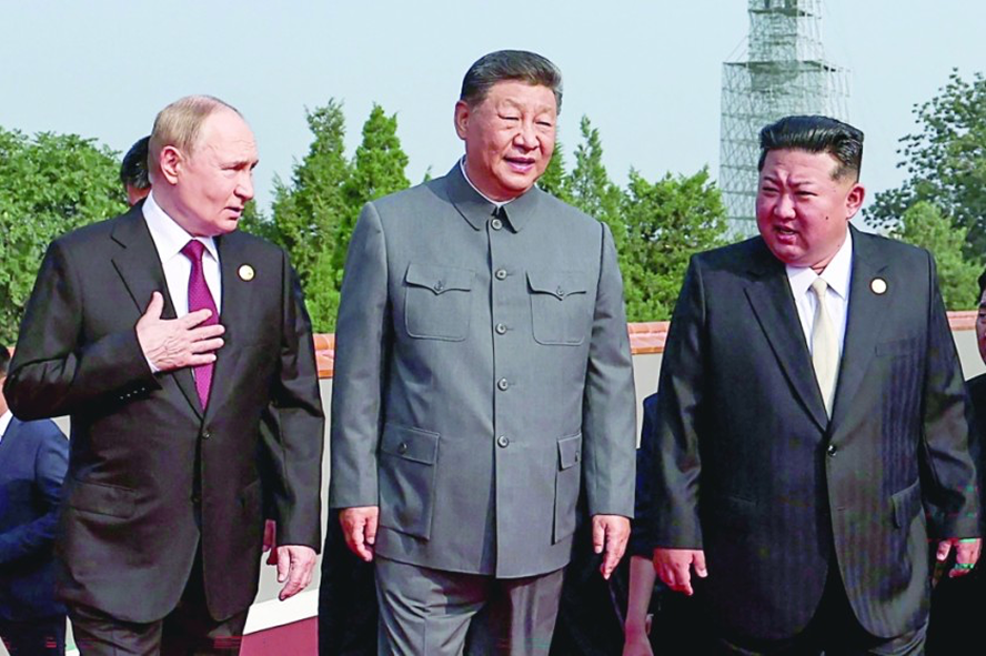 Three world leaders walking outdoors during a formal event with greenery and a tower in the background.